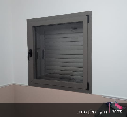 חלון עם תריס סגור על קיר לבן